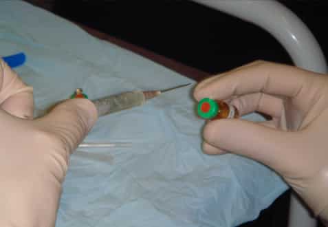 hands holding an syringe and vial